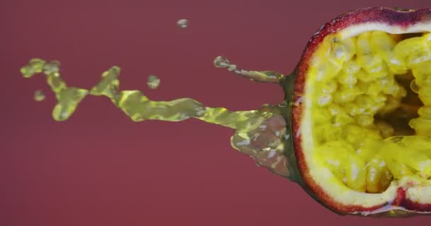 Vidéo verticale. Des éclaboussures de jus de fruits de la passion coulent de la pulpe naturelle sur fond de studio rouge avec espace de copie — Video