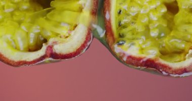 Dikey video. Pembe stüdyo arkaplanında tutku meyvesi akan taze egzotik biyolojik sıvı.