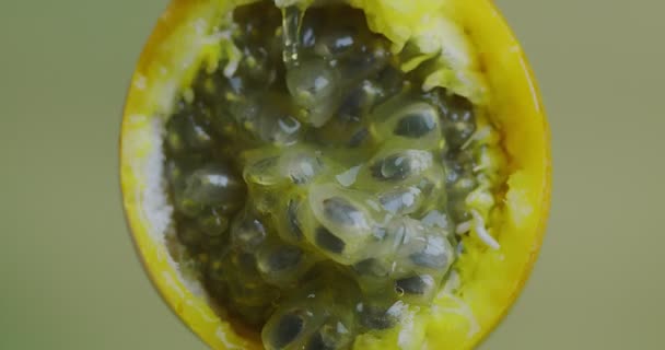 Granadilla сок течет на натуральной сочной фруктовой мякоти на зеленом фоне студии, концепция здорового питания, закрыть — стоковое видео