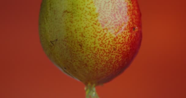 Nahaufnahme Video-Birnensaft, der von Früchten auf orangefarbenem Studiohintergrund herunterfließt, mit Kopierplatz für Werbung für gesunde Ernährung — Stockvideo