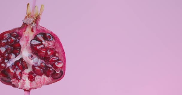 Succo scorre giù dalla frutta melograno su sfondo studio rosa con spazio copia, concetto di alimentazione sana — Video Stock