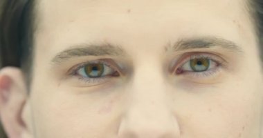 Kafkasyalı genç bir erkeğin 4K videosunu kapat. Kahverengi gözlü adam kameraya bakar. Görüş bakımı