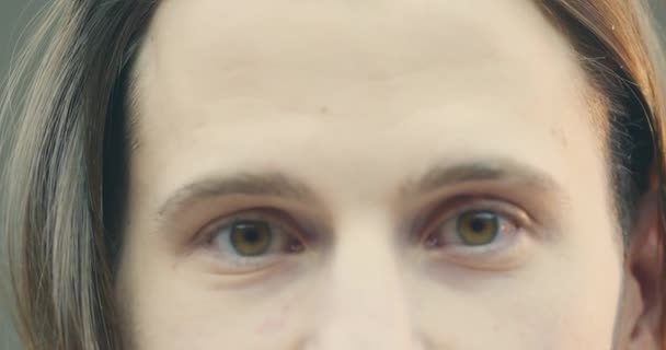 Gros plan vidéo 4k du visage masculin avec des yeux bruns aimables. Happy guy fixe les cheveux en regardant la caméra, concept de soins des cheveux. — Video