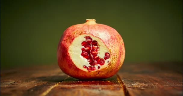 Stop motion of fresh pomegranate slicing on wooden cutting board in kitchen. 4k video on green backdrop. Vegan cooking — Stock Video