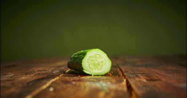 Stop moto di affettatura di cetriolo su tagliere in legno in cucina. 4k video su sfondo verde. Vegan cottura insalata — Video Stock