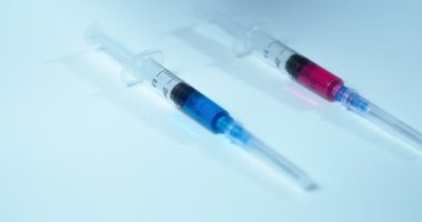 Aşı seçimi. Mavi ve kırmızı aşılar ya da diğer ilaçlarla dolu şırıngalar. Doktor bilim adamının elinin yakın çekim videosu.