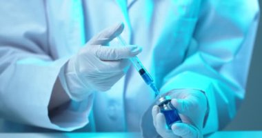 COVID-19 aşı kampanyası. Şırıngayı Coronavirus aşısıyla dolduran doktor, videoyu kapat.