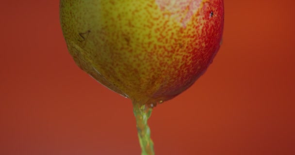 Närbild video päron juice flyter ner från frukt på ljusa orange studio bakgrund med kopia utrymme för annons — Stockvideo