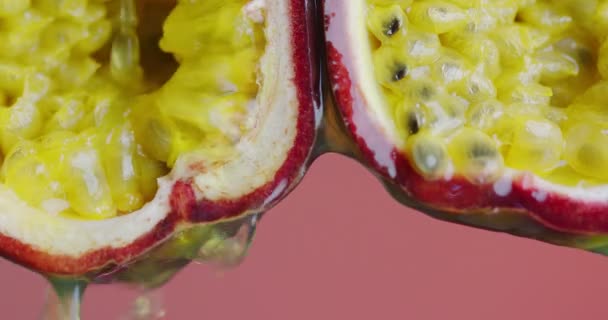 Succo di frutto della passione scorrono giù dalla polpa succosa biologica bio su sfondo rosa studio, sano cibo vegano tropicale esotico — Video Stock