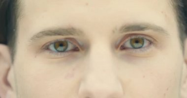 Erkek yüzüne yakın dur. Yakışıklı adam kahverengi gözleri açık. Beyaz, genç bir erkek kameraya bakıyor. 4K videosunu kapat