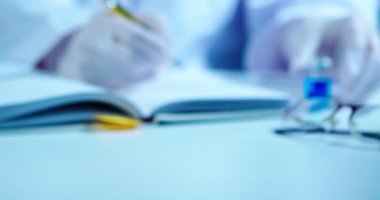 Aşı araştırmaları, bilim adamı doktor çalışma sonuçlarını yazıyor ve mavi ilaçlı ampulü gösteriyor.