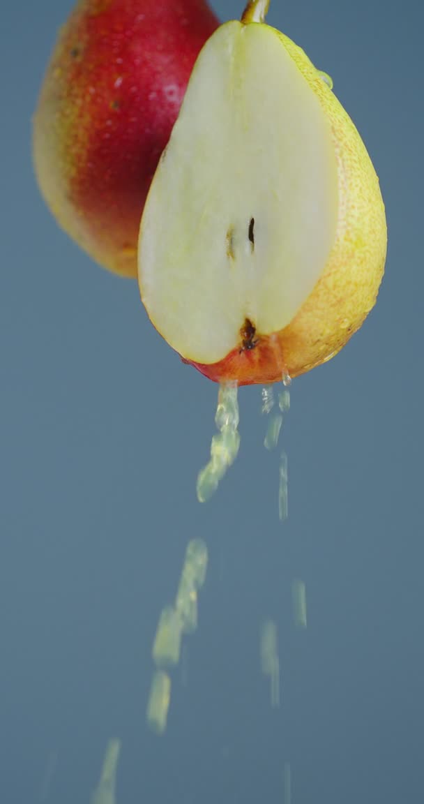 Vídeo Vertical. Suco de pêra fluir para baixo de frutas naturais em fundo estúdio azul, conceito de alimentação saudável, close-up — Vídeo de Stock
