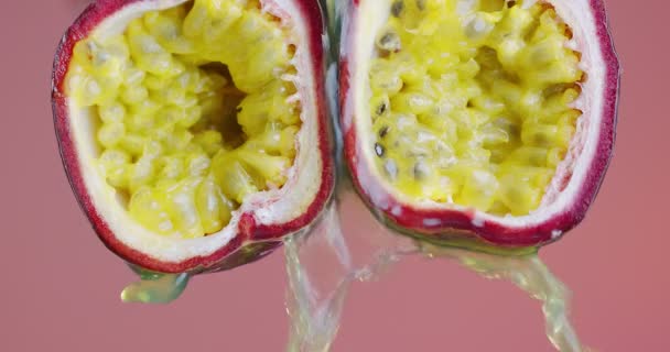 Gros plan vidéo jus de fruits de la passion coulant de pulpe juteuse sur fond de studio rose, exotique végétalien saine alimentation — Video