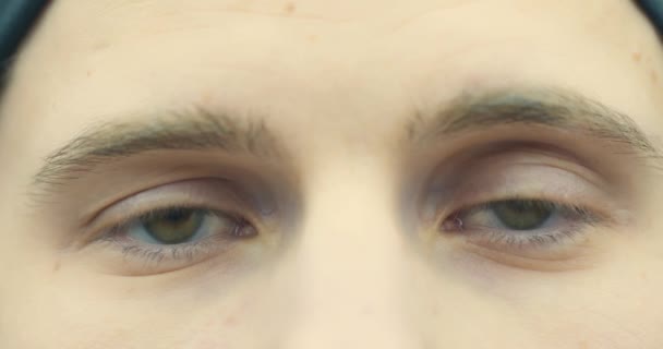 Närbild av den unge mannens ansikte. Manliga ögon med korrekta linser, naturlig skönhet. Killen tittar på kameran, blinkar, ler. 4K-video — Stockvideo