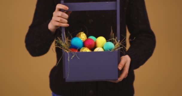 Los huevos de Pascua en la cesta de madera en las manos femeninas, la celebración de la fiesta religiosa cristiana de primavera — Vídeo de stock
