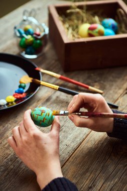 Dini bayram için hazırlanan kadın, boya fırçasıyla yumurta boyuyor. Sanatçılar atölyesi