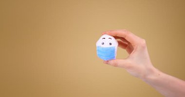 Elinde koruyucu tıbbi yüz maskesi olan komik Paskalya Yumurtası bej arka planda covid-19 salgını sırasında fotokopi alanı ile birlikte