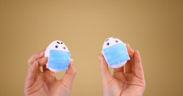 Социальная дистанция. Милые пасхальные яйца в защитных медицинских масках в руках во время пандемии ковид-19 — стоковое видео