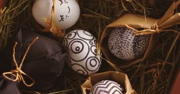 Uova di Pasqua con eleganti modelli monocromatici sdraiati sul fieno rotante, primo piano video vista dall'alto — Video Stock