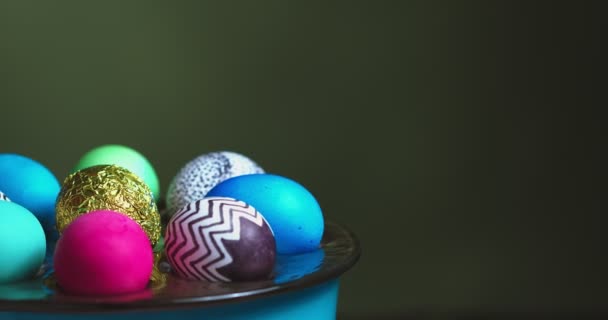 Крупним планом відео барвистих великодніх яєць на обертовій тарілці на зеленому фоні з місцем для тексту — стокове відео