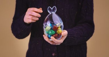 Paskalya kutlaması için dişi cam vazoyu açıyor. Renkli bıldırcın yumurtaları boyanıyor. Video kapanıyor.