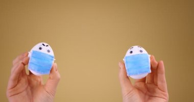 Sosyal mesafe. Koruyucu tıbbi maskeli Paskalya Yumurtaları. Covid-19 salgını sırasında tatil. Stüdyo videosunu kapat