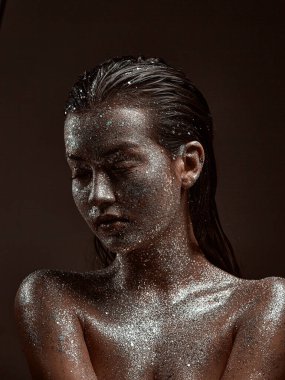 Gümüşten parıltılı makyajlı bir kadın, ışıl ışıl vücut sanatı içinde cildi olan genç bir kız, stüdyo portresini kapat.