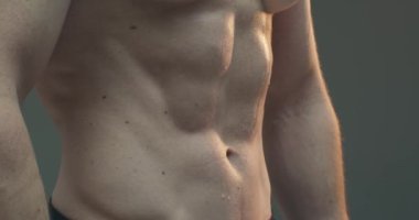Karın kasları. Erkek, çıplak ve eğitimli gövdesinin 4K videosunu kapat. Formda olduğunu gösteren atletik adam.