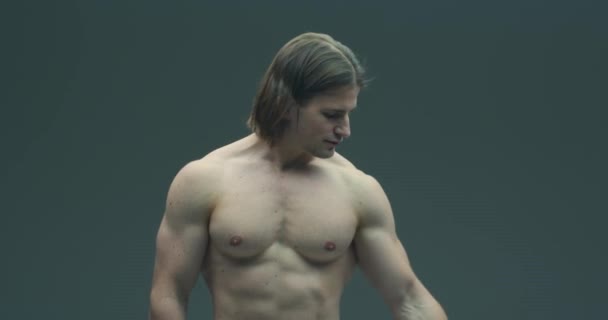 Homem fisiculturista sem camisa mostrando músculos bíceps em fundo de estúdio cinza. Forte atleta de aptidão muscular com corpo apto — Vídeo de Stock