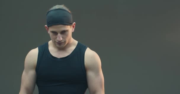 Sebevědomý atletický muž na šedém pozadí studia s kopírovacím prostorem pro motivační reklamní text. Snímek hlavy sportovní mladý chlap — Stock video