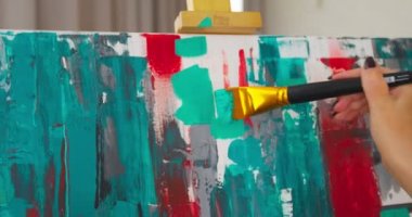 Modern kadın sanatçı büyük tuvalde renkli, soyut yağlı boya resim yapıyor. Yakın çekim Video