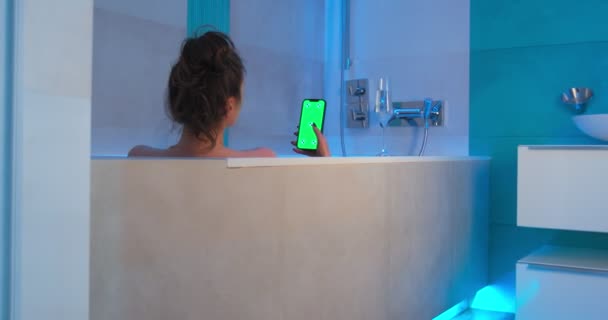 Green screen, chroma key of phone. Greenscreen of chromakey mockup. Lonely girl with smartphone in bath swiping content — Stock Video