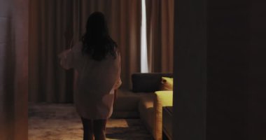 Otel odasındaki genç kadın pencerenin perdesini açıyor, dışarı bakıyor. Yeni bir motivasyon hissediyor. Modern evde yeni bir güne başlıyor.