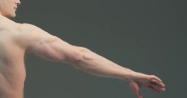 Erkek el kasları. Gri stüdyo arka planında pazılar ve trisepsler gösteren sporcu bir adam.