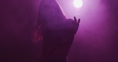 Gece kulübünde dumanlı ve mor ışıklı genç dansçı kız. Modern dansın 4k videosu