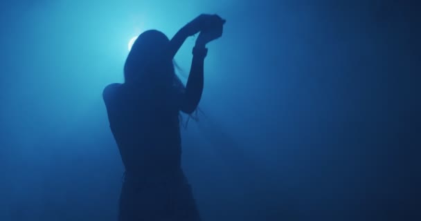 Dansând fată tânără în nor de fum, albastru noapte club lumina. Dans modern, video 4k. Misterioasă siluetă feminină în mișcare — Videoclip de stoc