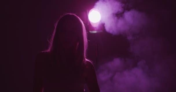 Silueta de joven bailarina en luz violeta de neón y humo. Mujer y neblina misteriosa en la noche — Vídeo de stock