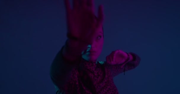 Νεαρή κοπέλα μικτής φυλής που χορεύει έθνικ χορό στο νέον στούντιο φως. Γυναίκα ερμηνεύτρια κινείται τα χέρια μπροστά από την κάμερα — Αρχείο Βίντεο