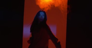 Dans eden genç kız stüdyoda dumanla renkli ışıkta serbest dans ediyor. Modern yaşam tarzı, rap ve hiphop