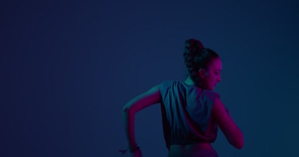 Cool joven mestiza bailando danza africana ardiente en luz de estudio de neón. Artista femenina profesional — Vídeos de Stock