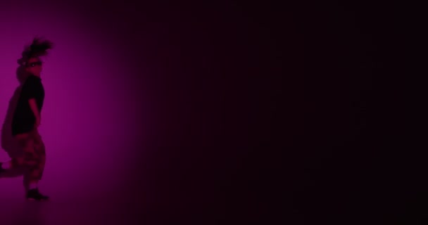 Стильная молодая девушка-подросток крутые танцы весело в центре внимания в неоновом розовый свет движется слева направо листья сцены — стоковое видео