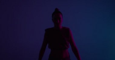 Neon Stüdyo ışığı altında dans eden genç melez kız. Profesyonel kadın oyuncu el kaldırıyor.