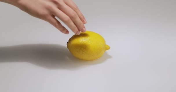 Tourner à la main citron fruit dans l'eau, citron naturel sur fond de studio blanc, vitamines et concept de saine alimentation — Video