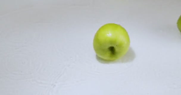 Manzanas verdes rodando en el agua rápidamente, frutas naturales en el fondo del estudio blanco, vitaminas y concepto de alimentación saludable — Vídeos de Stock