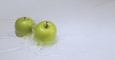 Su grevinde yeşil elmalar, beyaz stüdyo arka planında doğal meyveler, vitaminler ve sağlıklı beslenme konsepti.