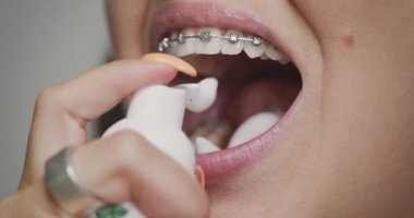 Diş hijyeni. Diş teli temizleyen bir kız, diş macununu temizleyerek ağız boşluğu temizleyen bir kız. Ortodonti ve diş sağlığı