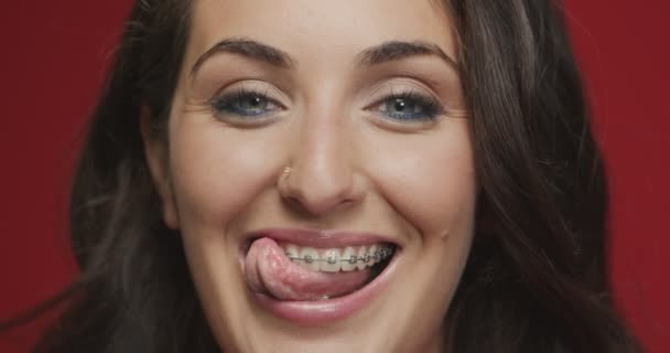Όμορφη γυναίκα με λευκά δόντια και σιδεράκια που δείχνουν γλώσσα. Οδοντιατρική περίθαλψη. Ορθοδοντική θεραπεία. Κλείσιμο βίντεο — Αρχείο Βίντεο