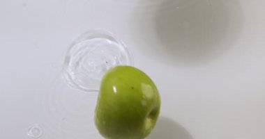Yeşil elmalar suyun üzerinde sıçrıyor, doğal meyveler, üst manzara. Vitaminler, sağlıklı beslenme konsepti