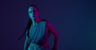 Havalı genç melez kız neon ışıkta ateşli dans ediyor. Profesyonel kadın sanatçı, ifade ve ritim