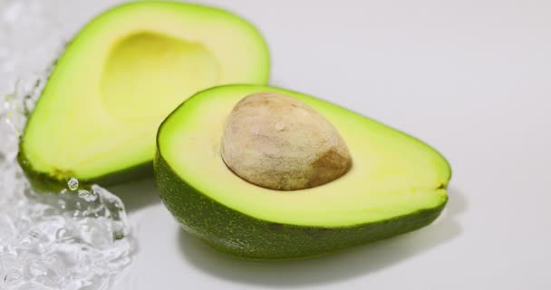 Rijp avocado helften liggend in stromend water. Natuurlijk biologisch fruit. Vitaminen, gezond eten concept — Stockvideo